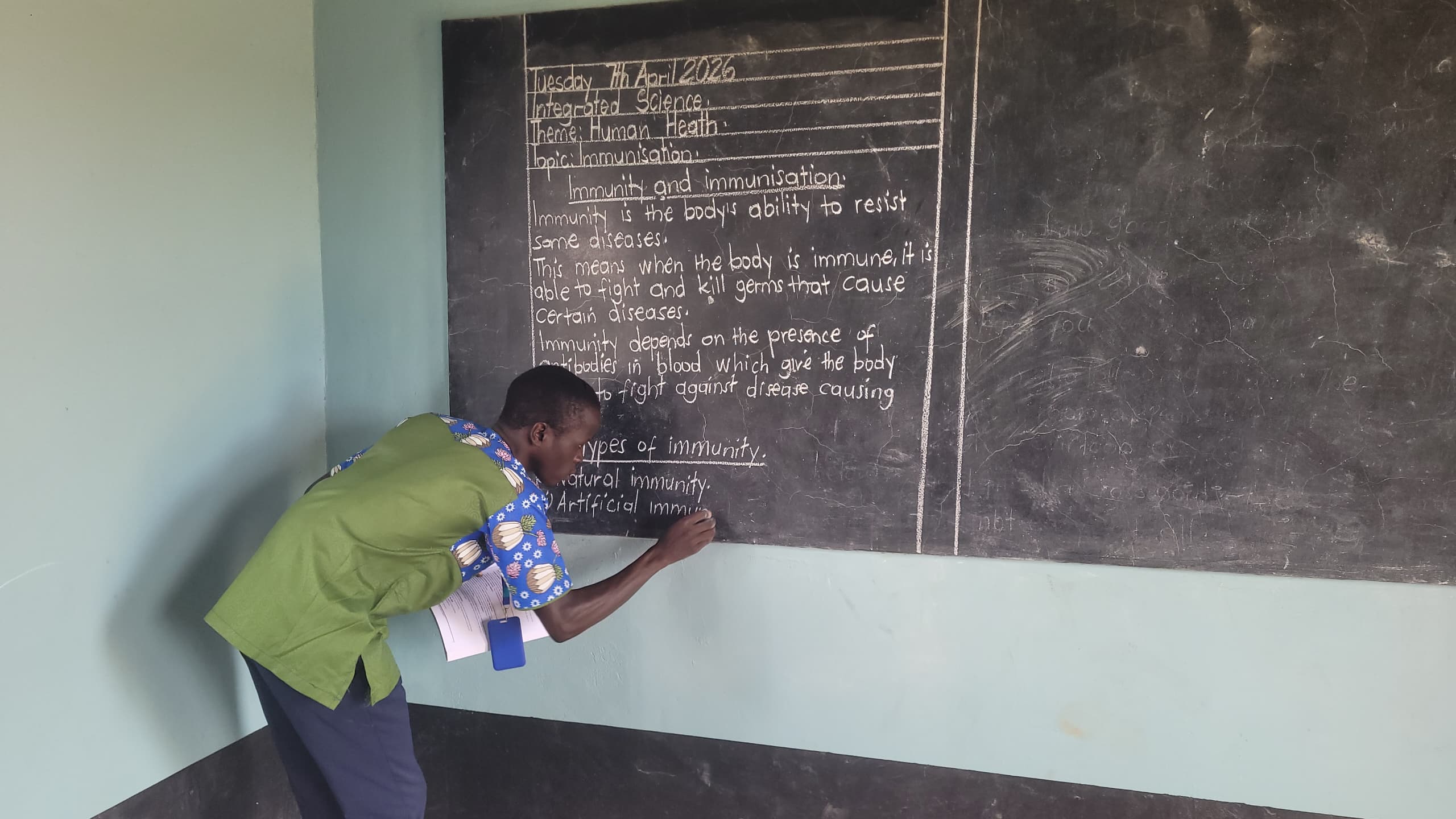 A teacher writing the immunity and immunisation lesson on the chalkboard at Hope Bridge